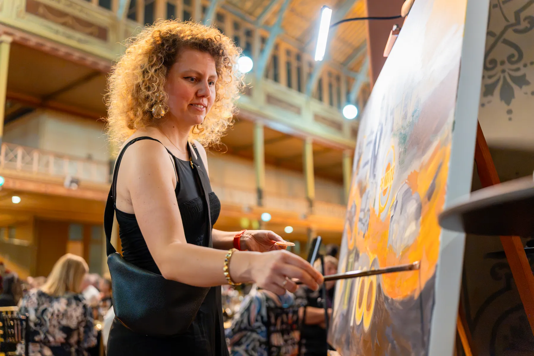 Olga mixing colours beside the Penrite painting at the gala